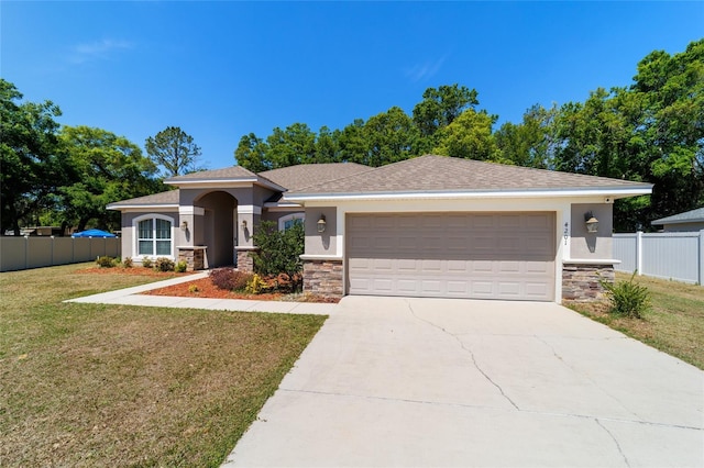 view of front of house with a front lawn, stucco siding, an attached garage, and fence