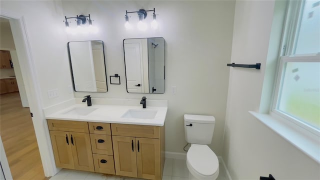 full bath with baseboards, double vanity, a sink, and toilet
