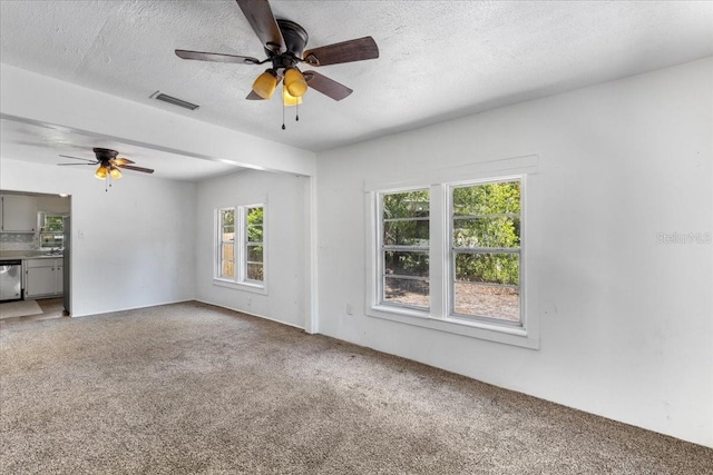 carpeted empty room featuring a textured ceiling, visible vents, and a ceiling fan