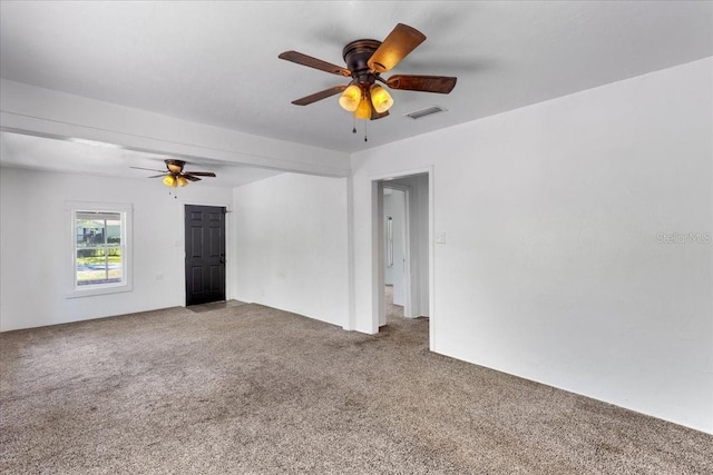 empty room featuring carpet floors, visible vents, and ceiling fan