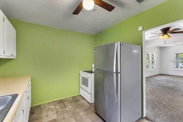 kitchen with freestanding refrigerator, white cabinetry, electric range, and ceiling fan