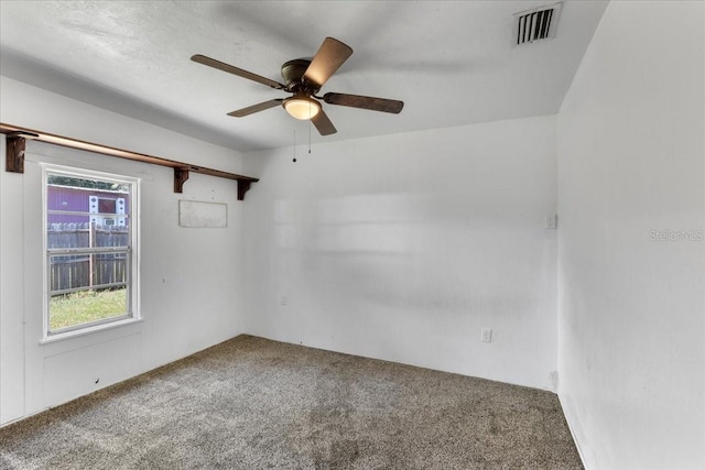 carpeted empty room featuring visible vents and a ceiling fan