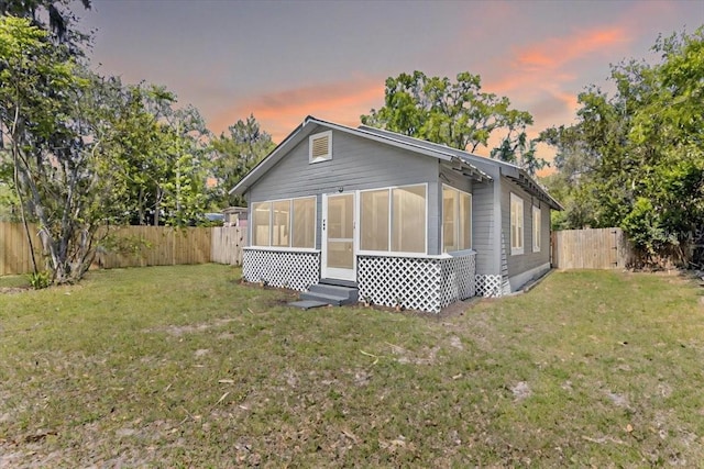 exterior space featuring a sunroom, a fenced backyard, and a yard