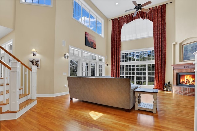 living room featuring a wealth of natural light, a fireplace, wood finished floors, and a ceiling fan