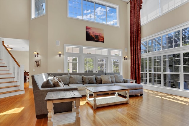 living room with plenty of natural light, a high ceiling, wood finished floors, and stairway