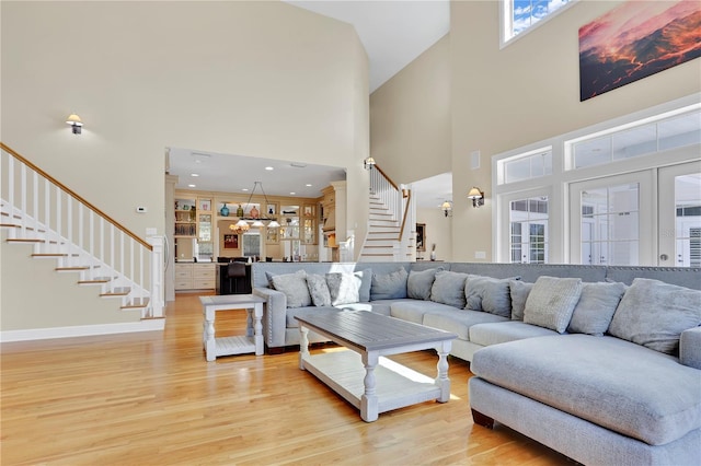 living room with stairway, recessed lighting, baseboards, a high ceiling, and light wood-style floors