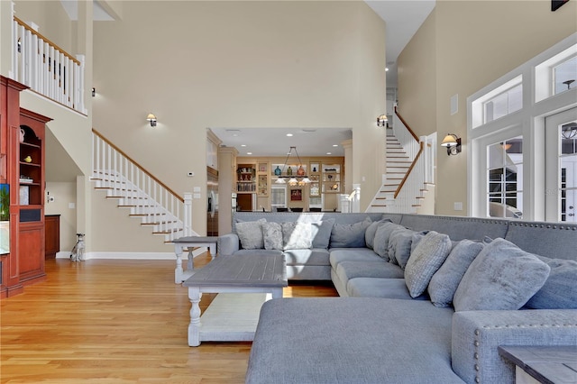 living room featuring baseboards, light wood-style floors, stairway, and built in shelves