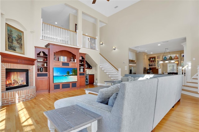 living room with stairs, light wood-type flooring, and a brick fireplace