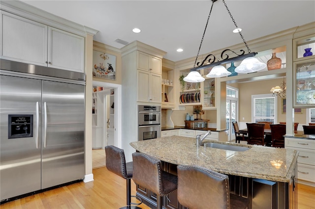 kitchen featuring open shelves, light wood-type flooring, a sink, visible vents, and appliances with stainless steel finishes