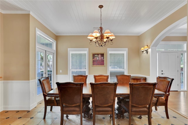 dining area featuring a wainscoted wall, arched walkways, crown molding, and a chandelier