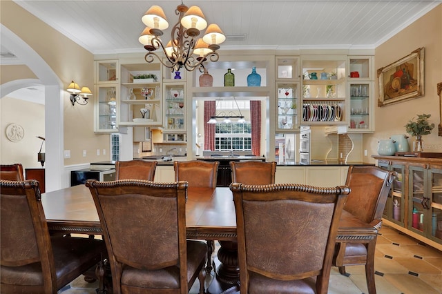 dining space with arched walkways, ornamental molding, and a chandelier