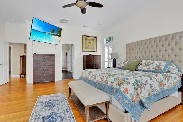 bedroom featuring ornamental molding, baseboards, visible vents, a ceiling fan, and wood finished floors