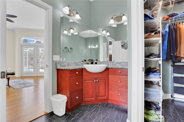 bathroom featuring baseboards, a ceiling fan, vanity, french doors, and a walk in closet