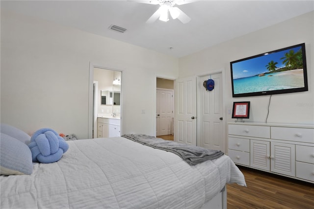 bedroom featuring a ceiling fan, dark wood-type flooring, ensuite bath, and visible vents