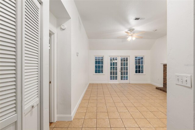 unfurnished room with ceiling fan, light tile patterned floors, baseboards, vaulted ceiling, and french doors
