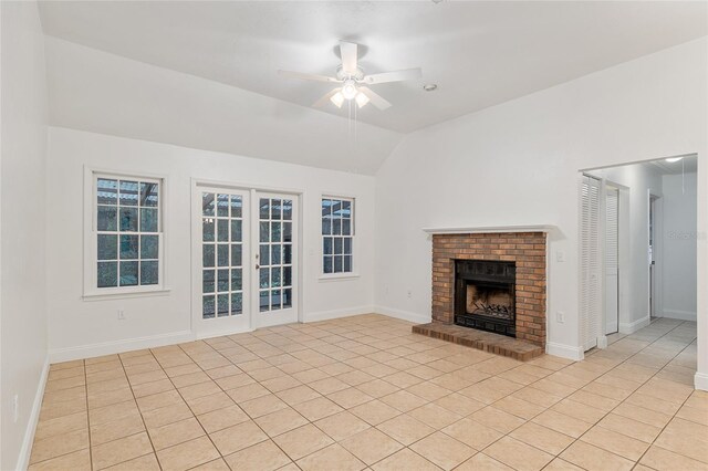 unfurnished living room featuring ceiling fan, a fireplace, lofted ceiling, light tile patterned floors, and baseboards