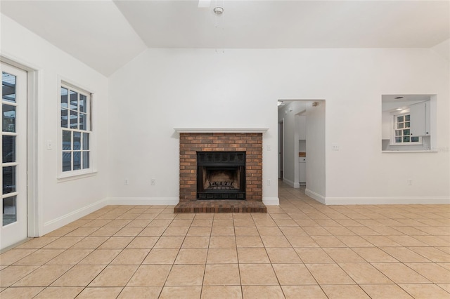 unfurnished living room with vaulted ceiling, a brick fireplace, and baseboards