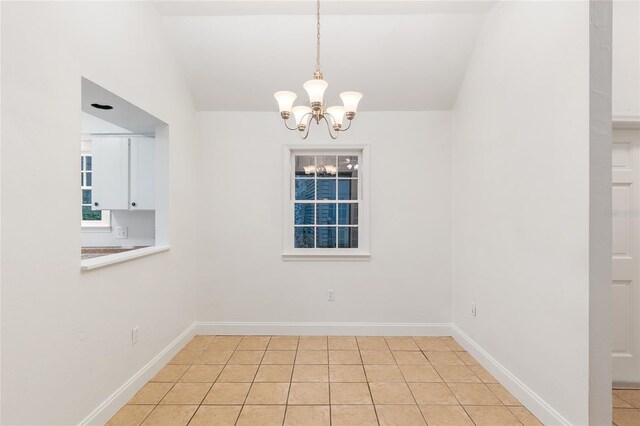 unfurnished dining area with a chandelier, light tile patterned floors, and baseboards