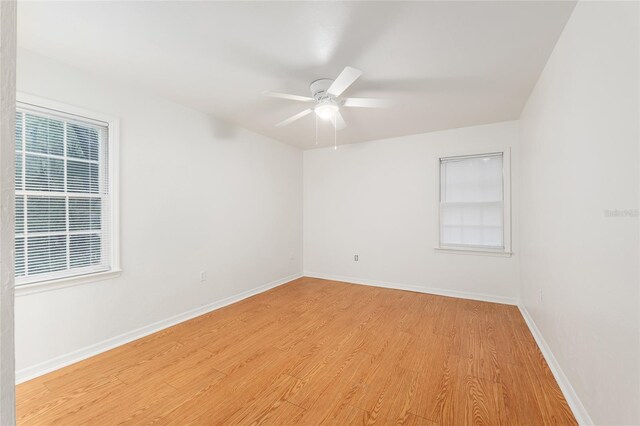 spare room with light wood finished floors, a ceiling fan, and baseboards