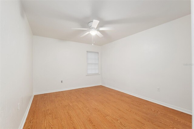 spare room featuring a ceiling fan, light wood-style flooring, and baseboards