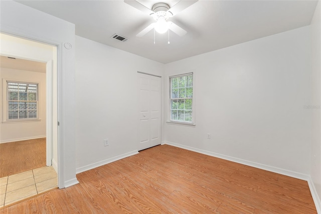 empty room featuring light wood-style flooring, a ceiling fan, and baseboards