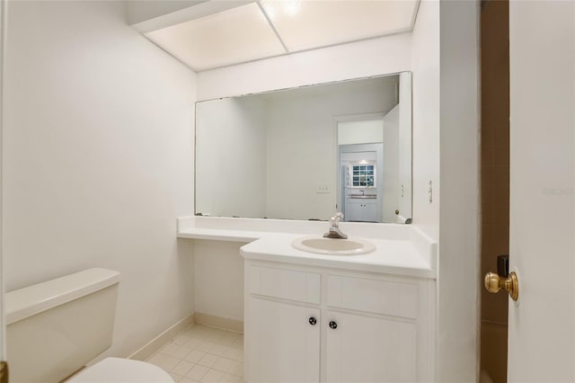 half bath with toilet, vanity, tile patterned flooring, and baseboards