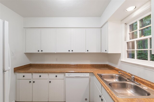 kitchen featuring white dishwasher, a sink, and white cabinets