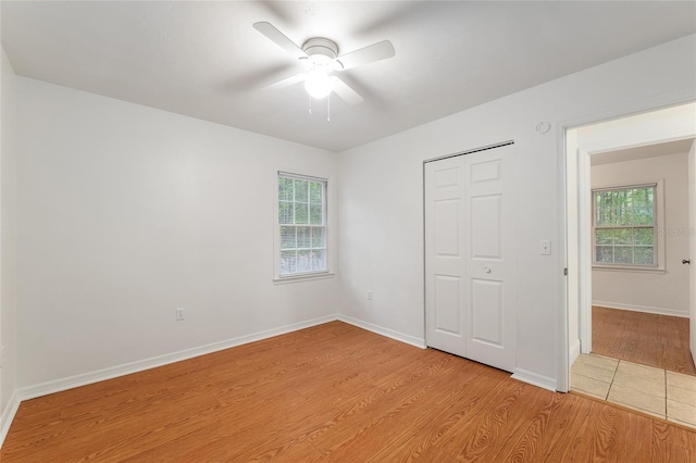 unfurnished bedroom featuring light wood-style flooring, baseboards, a closet, and ceiling fan
