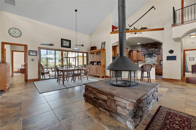 living area with a towering ceiling, baseboards, visible vents, and a wood stove