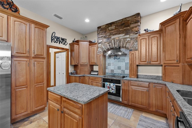 kitchen with range hood, decorative backsplash, light stone counters, visible vents, and appliances with stainless steel finishes