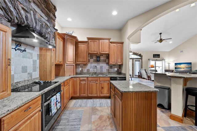kitchen with light stone countertops, a sink, black electric stovetop, and stainless steel oven