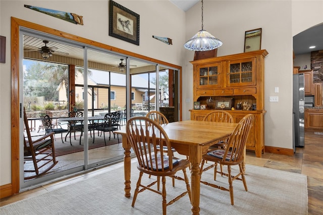 dining area with a high ceiling, arched walkways, baseboards, and ceiling fan