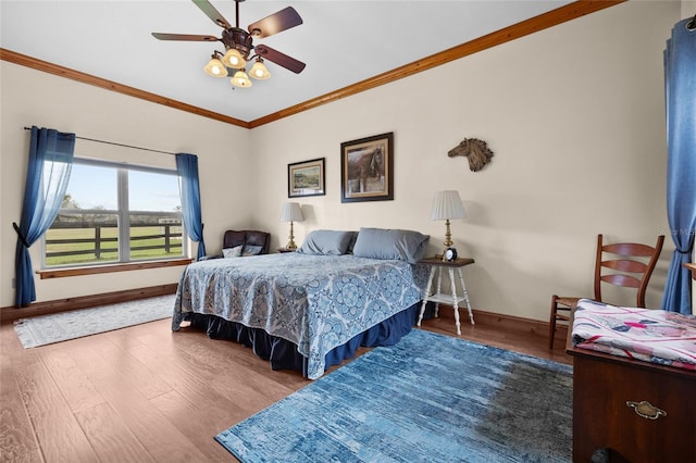 bedroom with baseboards, ornamental molding, and wood finished floors