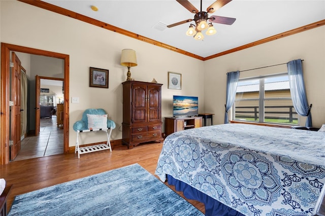 bedroom featuring visible vents, crown molding, baseboards, wood finished floors, and a ceiling fan