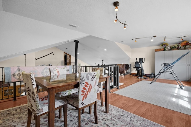dining room with a textured ceiling, lofted ceiling, light wood finished floors, and visible vents