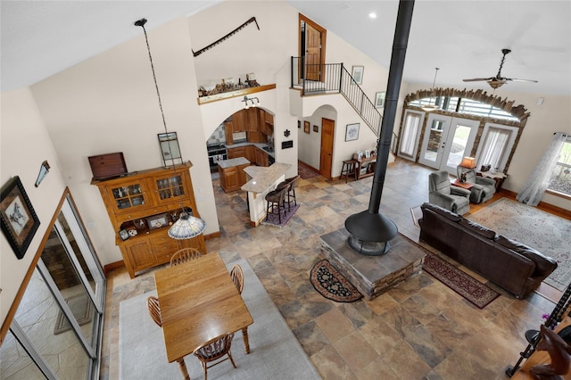 living room with arched walkways, high vaulted ceiling, a wood stove, and a ceiling fan