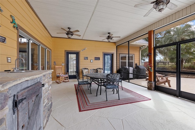 sunroom featuring ceiling fan, a sink, and outdoor dining space