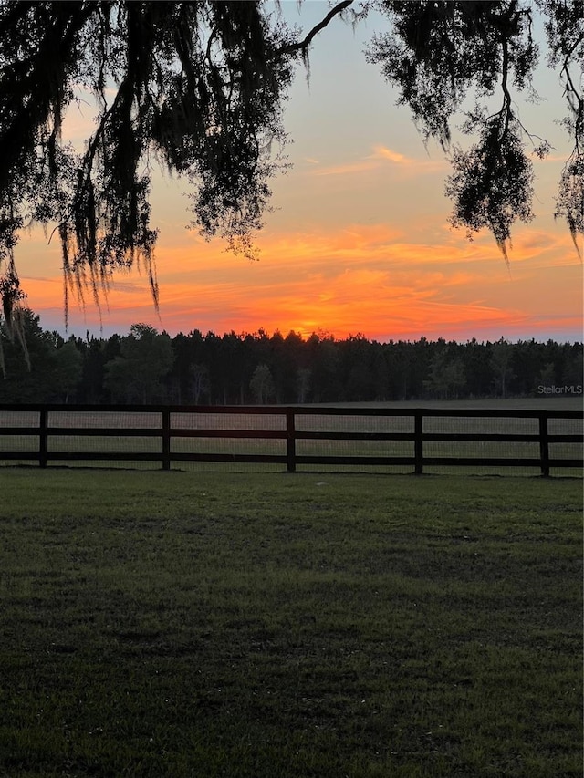 view of yard with fence and a rural view