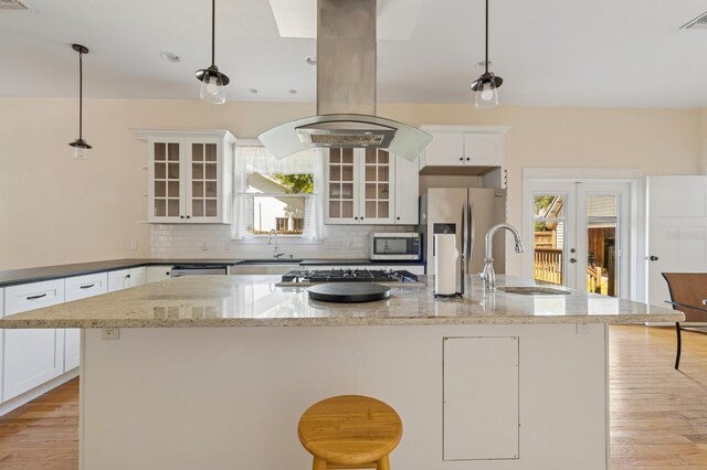 620 NE 6th Ave, Gainesville, FL 32601 - kitchen with decorative backsplash, appliances with stainless steel finishes, a center island with sink, a sink, and white cabinetry