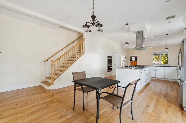 620 NE 6th Ave, Gainesville, FL 32601 - dining room with visible vents, light wood-type flooring, stairway, baseboards, and a chandelier