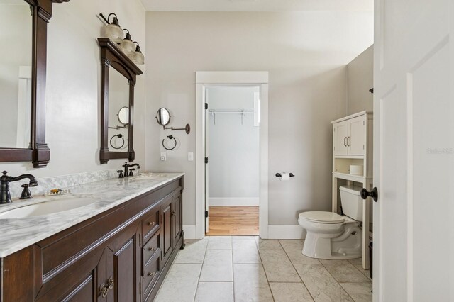 620 NE 6th Ave, Gainesville, FL 32601 - bathroom featuring double vanity, a sink, baseboards, and toilet