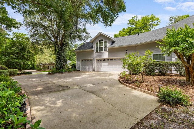 view of front of home featuring concrete driveway, a shingled roof, and a garage