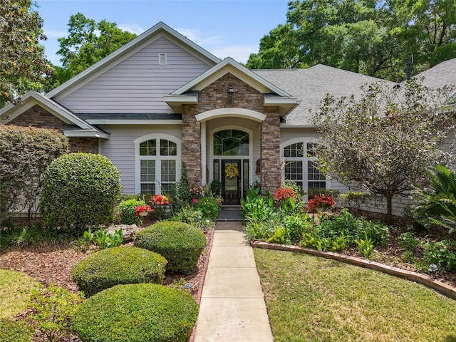 view of front of house featuring a shingled roof and stone siding
