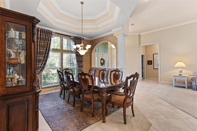 dining space with crown molding, light tile patterned floors, an inviting chandelier, a tray ceiling, and ornate columns