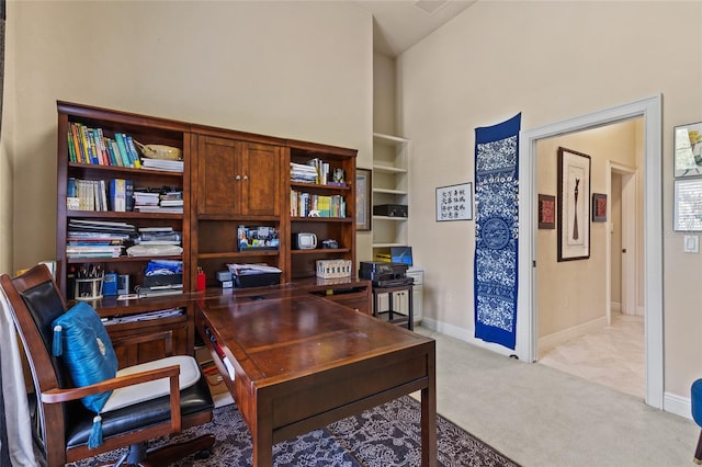 office space featuring baseboards, light carpet, and a towering ceiling