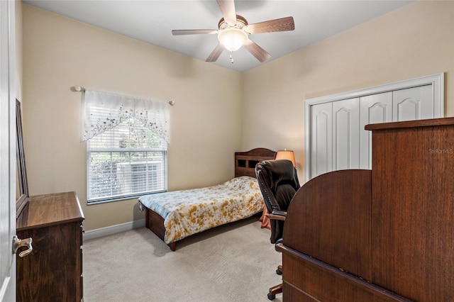 bedroom with a ceiling fan, baseboards, light colored carpet, and a closet