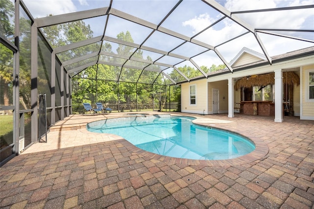 view of pool featuring a patio area, glass enclosure, and a pool with connected hot tub