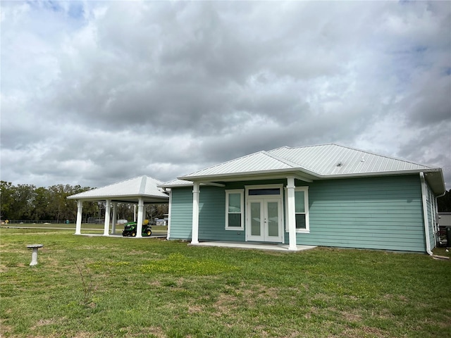 rear view of house with a lawn, french doors, and metal roof