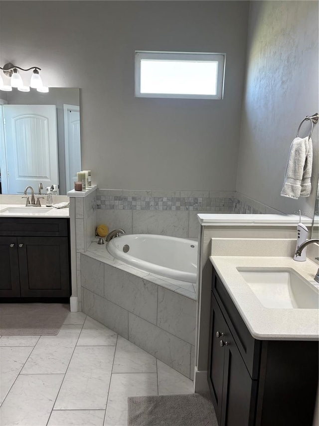 bathroom featuring a sink, a garden tub, and two vanities