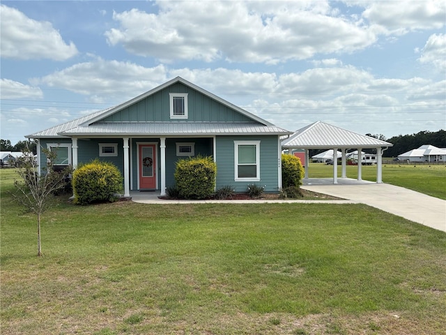 view of front facade featuring board and batten siding, metal roof, a carport, a front lawn, and concrete driveway